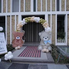 A welcoming entrance for a teddy bear-themed baby shower. Two large teddy bear cutouts stand guard at the balloon arch, creating a sweet and inviting entryway for the celebration.