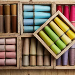 A flat-lay composition of colorful yarn cones organized in wooden boxes. This artistic arrangement showcases the brand's color palette in a creative and visually appealing way.