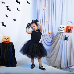 Showcasing a different product from the same brand, this is a full shot of a child's cat costume. The model's playful pose and the carefully arranged Halloween background create a fun, energetic image that effectively markets the product for party or event wear.