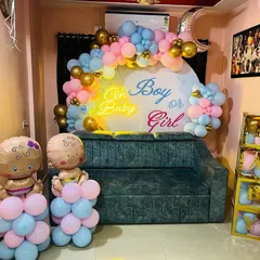 A fun "Oh Boy or Girl?" gender reveal party setup. The decor includes a custom backdrop, pink and blue balloon garlands, and cute baby-shaped foil balloons.