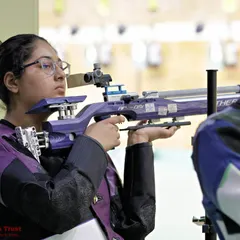 The intense focus of a rifle shooter during a competition. Our training prepares athletes for the high-stakes environment of championships.