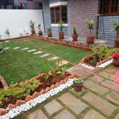 This front yard was transformed with a new lawn, stepping stone path, and carefully arranged potted plants along the house. The design creates a welcoming entrance with clean lines and organized greenery.