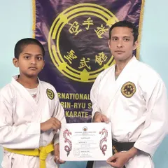 This image captures the formal moment of recognizing a student's progress. The certificate represents not just a new rank, but the embodiment of the Dojo Kun principles of effort and sincerity.