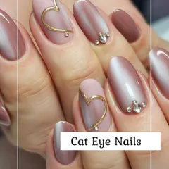 A beautiful example of cat eye nails, featuring a magnetic, shimmering effect on a mauve base. The design is elevated with 3D gold heart accents and carefully placed rhinestones for a touch of glamour.