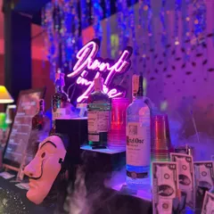 The complete Money Heist bar setup in action. A "Drunk in Love" neon sign, a Dali mask prop, and dramatic smoke effects create an immersive atmosphere for a memorable wedding cocktail night.