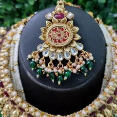 The beautiful maang tikka from this set, featuring the same red engraved pendant design to create a perfectly coordinated bridal look.
