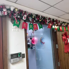 Christmas decorations for an office or home entryway. We installed a festive garland over the door with ornaments, a snowman, candy canes, and a 'Merry Christmas' banner.