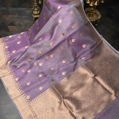 A lovely lavender organza silk saree with gold butis and a wide gold border. The sheer fabric and soft color create an ethereal and elegant look.