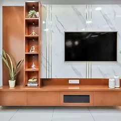 A luxurious TV unit combining a rich wood console with a marble-finish wall panel and gold inlay details. A tall, lit display shelf on the side adds a touch of elegance.