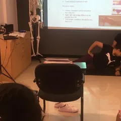 Correcting form is crucial. Here, a trainer adjusts a student's posture during a demonstration of a core exercise, linking theory to practical application.