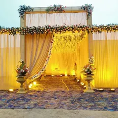 An evening shot of the same grand wedding entrance, showing how the spotlights highlight the floral decor and create a dramatic, welcoming ambiance for guests.
