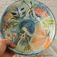 A close-up of a hand-painted plate featuring a vibrant, abstract floral design. Each brushstroke is carefully applied to create a one-of-a-kind piece of functional art for your dining table.