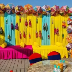 This quirky Mehendi seating area features a backdrop of bright drapes, hanging puppets, and Rajasthani umbrellas. It's a fun and festive design that doubles as a great photo opportunity.