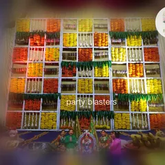 This image shows the floral grid backdrop as part of a larger baby shower setup. In front of the wall of flowers, traditional idols and offerings are placed, integrating the decor seamlessly with the ceremonial proceedings.