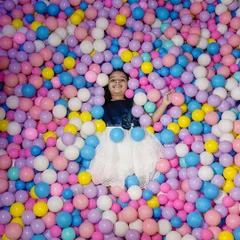 A vibrant and fun photo of a girl having the time of her life in a massive ball pit. This shot is all about capturing the pure, unfiltered joy of being a kid.