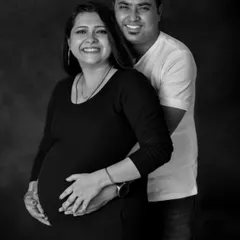 The pure happiness of starting a family together. This classic black and white studio portrait captures the joyful smiles and close embrace of an expecting couple, a perfect memory of this special time.