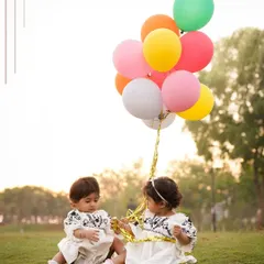 Two little ones sharing a moment with a bunch of colorful balloons during an outdoor park session. Props can add a touch of whimsy and fun to children's portraits.