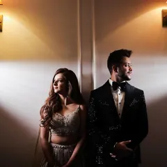 A stylish portrait of a couple for their engagement, using dramatic spotlighting against a plain wall to create a modern and clean look.