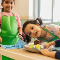 Smiles and splashes of color. Abhyudita and Charlotte are having a blast in their art class, protected by their aprons and free to get creative.