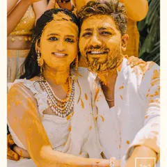A happy portrait of the couple covered in Haldi paste, smiling for the camera. This image perfectly encapsulates the joyful and messy fun of the ceremony.