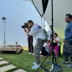 Here I am in action during an outdoor shoot. You can see the lighting setup with a large diffuser to create soft, flattering light even under the sun.