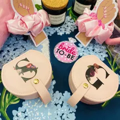 A close-up of our 'Bride-to-Be' themed bridesmaid hamper. It features a personalised floral initial jewellery box, a satin scrunchie, and a rich mahogany scented candle, perfect for asking "will you be my bridesmaid?".