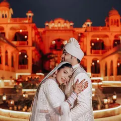 A tender embrace against the beautifully lit facade of Rajasthali Jaipur. We use the ambient light of your venue to create warm, romantic, and unforgettable night portraits.