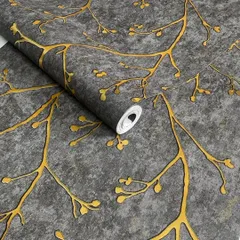 A close-up of a dark grey wallpaper roll with an embossed gold branch pattern.