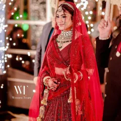 A beautiful bride looking regal in a classic red lehenga, perfectly complemented by our heavy polki choker set with green stone accents. This is a timeless look for any Indian wedding.