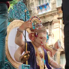 A side profile of the Kamathipura cha Mahaganpati idol during its journey. This angle highlights the idol's majestic posture and the detailed craftsmanship of the throne and ornaments.