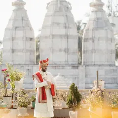 The groom in a moment of quiet reflection, with the traditional temple architecture in the background. This portrait is a beautiful blend of tradition and personal contemplation.