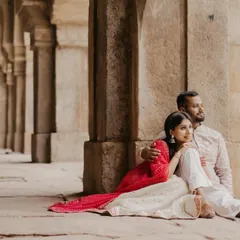 A quiet, intimate moment as a couple sits together against ancient stone pillars. The soft light and their relaxed pose convey a sense of comfort and timeless love during their heritage photoshoot.