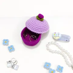 This cupcake-shaped ring box is perfect for keeping your favorite rings safe. This photo shows the lid open, revealing the storage space inside, surrounded by other jewelry.