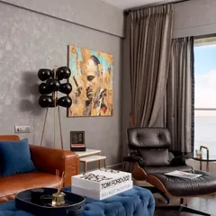 The den, a collector's haven. This space features a comfortable leather sofa, an Eames lounge chair, and shelving to display the client's favorite vinyls, cigars, and malts, all set against a moody, textured grey wall.