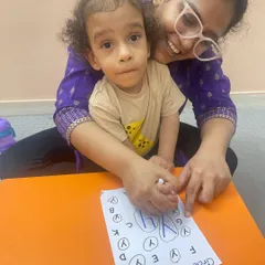 A mother helps her child circle the letter 'Y' on a worksheet, a great example of our hands-on approach to early literacy.