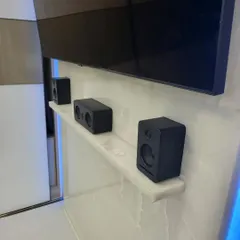 This photo shows the front speaker arrangement from the same Banashankri project. The center, left, and right channel speakers sit neatly on a shelf below the television, providing a clean, clutter-free look. Notice the absence of a bulky AVR box, which is a key benefit of this modern plug-and-play system.