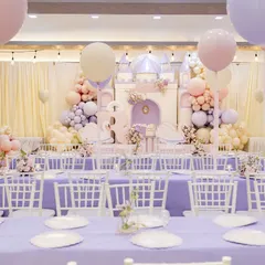 A wide view of Radha's "ONEderland" first birthday, where a pastel castle backdrop, swan props, and lavender tables created a fairytale setting fit for a princess.