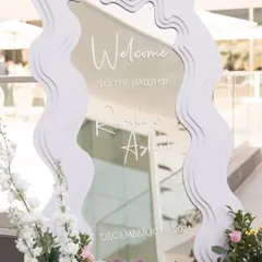 A modern, wavy mirror with custom calligraphy served as the welcome sign for this stylish Haldi event.