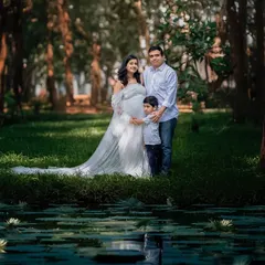 A beautiful portrait of the complete family by a lily pond. This wide shot captures a serene moment of togetherness as they await their new arrival.