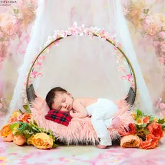 A sleeping newborn rests peacefully in a beautiful floral swing prop. This dreamy setup creates a magical, fairytale-like portrait.