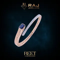 This modern rose gold kada showcases a sleek, open design, culminating in a striking blue gemstone set against a backdrop of sparkling CZ stones. Its architectural form and detailed meshwork offer a perfect blend of contemporary style and classic elegance.