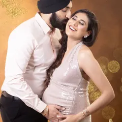 The joy of expecting, shared between partners. This candid moment captures a genuine laugh, showcasing the love and excitement of the journey. The glamorous sequin gown adds a touch of sparkle to this beautiful memory.