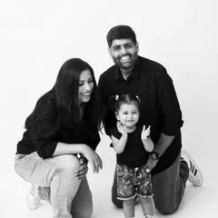 A happy family of three in a classic black and white portrait. Their genuine smiles and casual poses create a timeless and authentic image.