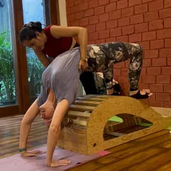 My approach to teaching is hands-on and personalized. Here, I am helping a student safely deepen her Chakrasana (Wheel Pose) using a spine corrector prop. This is how we build strength and flexibility with proper alignment, ensuring you learn the correct technique from day one.