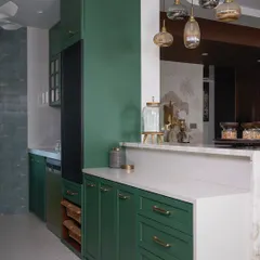 A wide shot of the green kitchen, highlighting the deep green cabinetry, open shelving for easy access, and the elegant pendant lights above the breakfast counter.