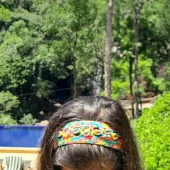 A view of the floral crochet headband against a natural, green background, highlighting its vibrant colors.