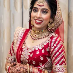 A classic North Indian bridal look in a stunning red lehenga. The makeup is timeless, with a focus on radiant skin, defined eyes, and a bold red lip.