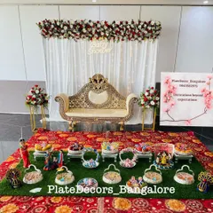 A complete baby shower stage decoration with a white and red floral theme. I arranged all the seer platters, including doll-themed and fruit baskets, to create a cohesive and festive look.