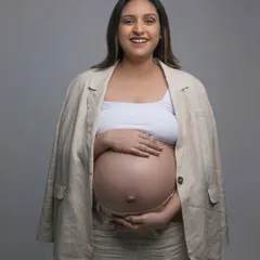 A classic maternity pose. The makeup is minimal and clean, designed to enhance her features naturally and create a timeless look for her photoshoot.