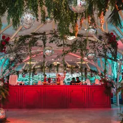 A look at the vibrant, red bar set against a backdrop of hanging greenery and disco balls for the "Jungle Disco" reception. The contrast of natural and glamorous elements defined the event's unique atmosphere.